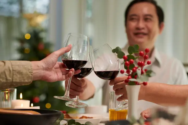 Christmas party guests toasting with wine glasses at Christmas dinner