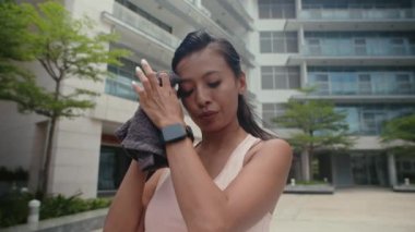 Düşük açılı bir bakış açısıyla, kız terini havluyla siliyor ve açık havada yapılan eğitimden sonra kalorilerin miktarına bakıyor.