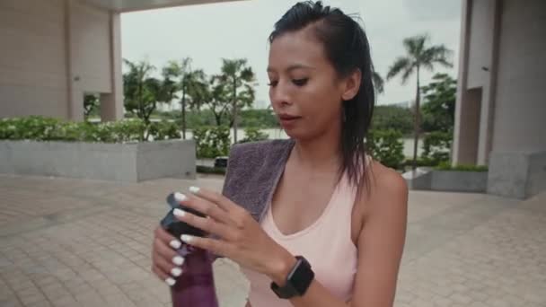 朝の運動後の水を飲む若い女性の中型ショット — ストック動画