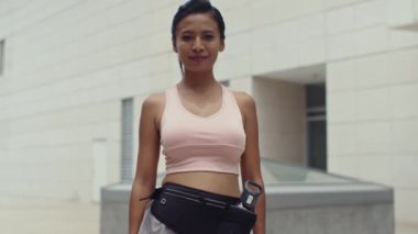 Açık havada spor yaptıktan sonra kameraya bakan neşeli Asyalı kadının portresini kaldır.