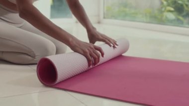 Antrenmandan sonra yoga minderini saran tanınmayan bir kadının görüntüsü.