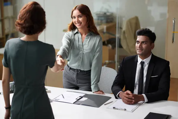 Cheerful company managers greeting new employee
