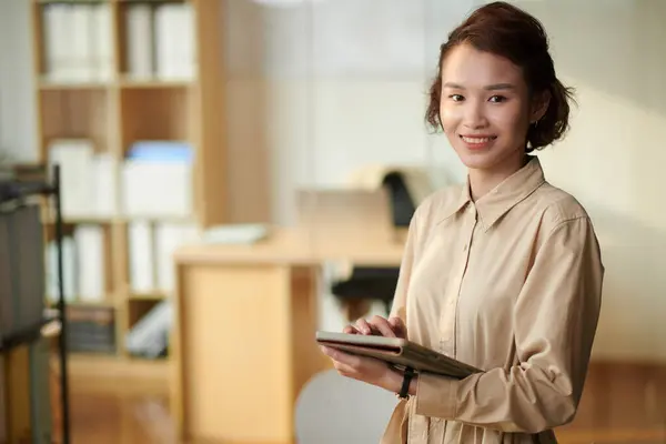 Portrait of cheerful young businesswoman with tablet computer working in office