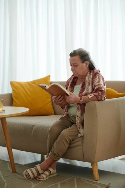 Seniorin Sitzt Auf Couch Wohnzimmer Und Liest Buch — Stockfoto