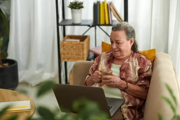 Mujer Mayor Descansando Sofá Bebiendo Viendo Programa Portátil — Foto de Stock