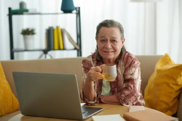 Fröhliche Ältere Frau Trinkt Tee Und Arbeitet Hause Laptop — Stockfoto
