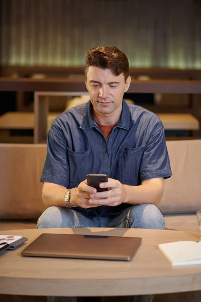 Portrait of mature businessman answering text messages from colleagues