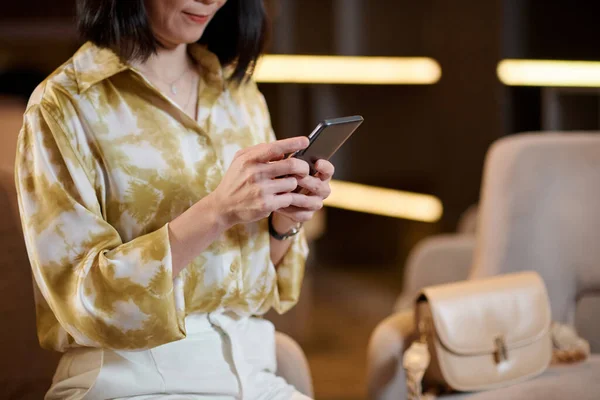Elegant business lady in silk blouse checking notifications on her smartphone
