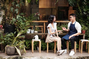 Kahveci barista gülümseyen müşteriyle flört ediyor.