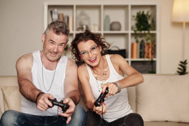 Neşeli orta yaşlı çift evde yarış oyunu oynuyor.