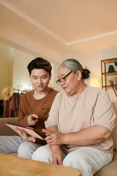 Seniorin Bittet Teenager Enkel Hilfe Bei Anwendung Auf Tablet Computer — Stockfoto