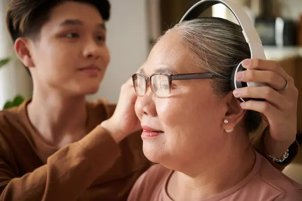 Jongeman Helpt Oma Heaphones Dragen Naar Muziek Luisteren — Stockfoto