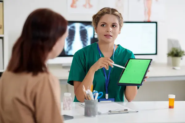 患者と話すときに緑色の画面をタブレットコンピュータで指すパルモノロジスト — ストック写真