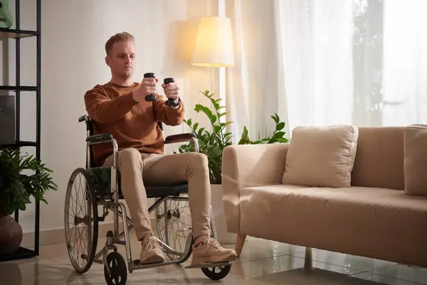 Schwerwiegender Junger Mann Rollstuhl Trainiert Hause Mit Kleinen Hanteln — Stockfoto