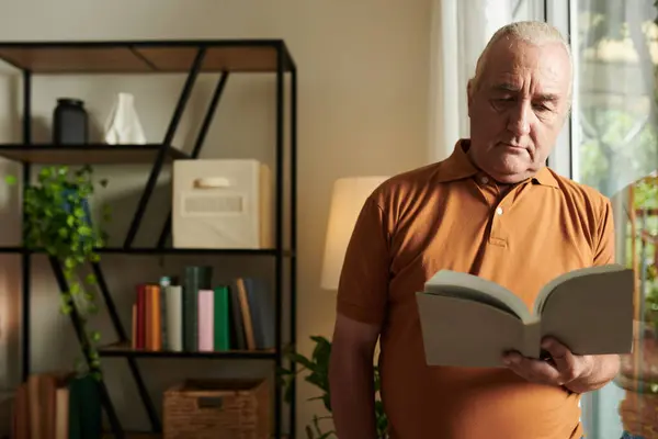 Vážný Starší Muž Stojící Velkého Okna Obývacím Pokoji Čtení Podmanivé — Stock fotografie