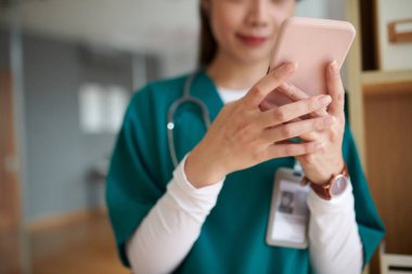 Önlüklü hemşire mola verdiğinde akıllı telefondan uyarıları kontrol ediyor.