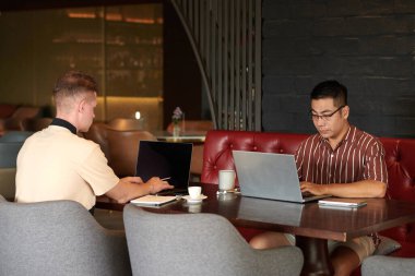 Kahve içen ve dizüstü bilgisayar üzerinde çalışan tüccarlardan oluşan bir ekip.