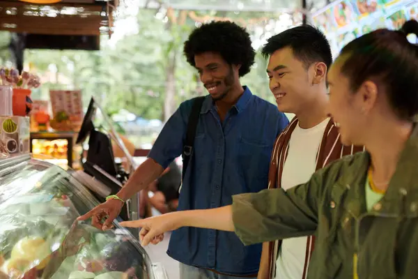Diverse group of friends shopping for food at market when wandering around city