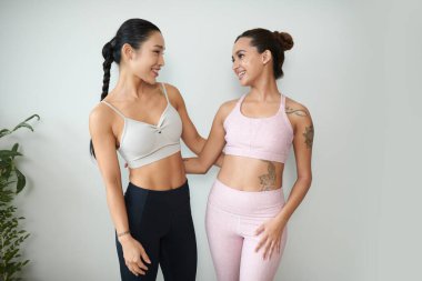 Spor sutyenli ve taytlı genç bir kadın birbirine bakıyor.