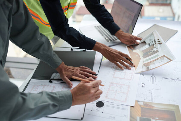 Architect and foreman discussing details on house renovation, checking blueprints and photos