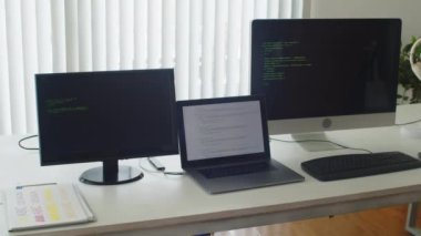 Ofisteki ekranlar üzerinde test modunda çalıştırılmış bilgisayarları olan programcı masasının ortanca kapatılması