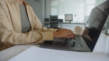 Ofiste otururken bilgisayarın klavyesine bir şey yazan tanınmayan bir kadının görüntüsü.