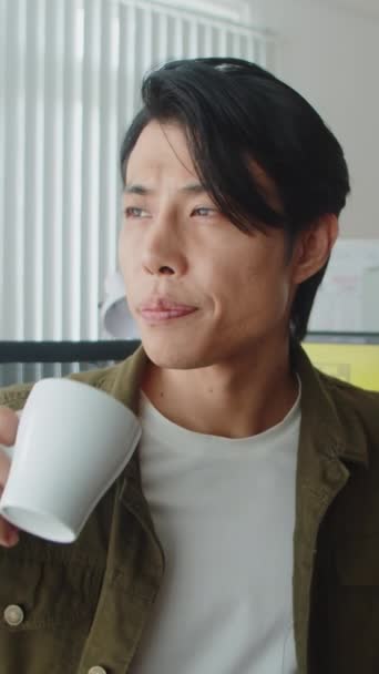 Κάθετη Προσωπογραφία Ασιάτη Εργαζόμενη Που Κοιτάζει Κάμερα Πίνοντας Καφέ Κατά — Αρχείο Βίντεο