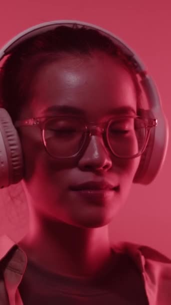 Pionowe Zbliżenie Portret Pogodnej Azjatki Noszącej Słuchawki Patrząc Kamerę Studio — Wideo stockowe