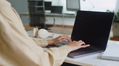 Ofiste çalışırken dizüstü bilgisayarla tanımlanamayan kadın yazılım mühendisinin kod yazma görüntüsü kesilmiş.