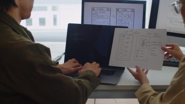 两名开发人员坐在办公室的数字设备前 按照指令测试新代码的背景图 — 图库视频影像