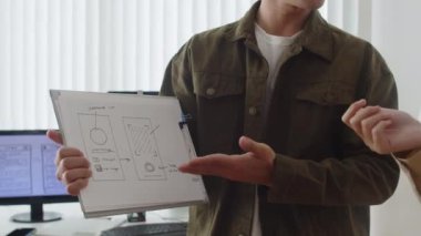 Ofiste çalışırken yeni mobil uygulamanın tasarımını tartışan iki testçinin kırpılmış görüntüsü