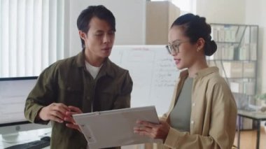 Genç bayan programcının, erkek proje yöneticisine iş planıyla birlikte ofis programlarını tartışan bir belgeyle orta boy görüntüsü.