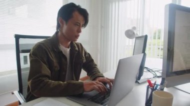 Modern ofiste dizüstü bilgisayarlar için yeni bir uygulama üzerinde çalışan düşünceli erkek yazılım mühendisinin orta boy görüntüsü.