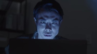 Bilgisayar sistemini hacklemeye çalışan bir adamın gece vakti dizüstü bilgisayarın önünde oturmasını kapat.