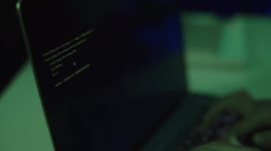 Yeşil LED ışığı altında geç saatlerde hackleme veya çalışırken bilgisayardaki kodlamayı yapan kişinin ellerini kapat
