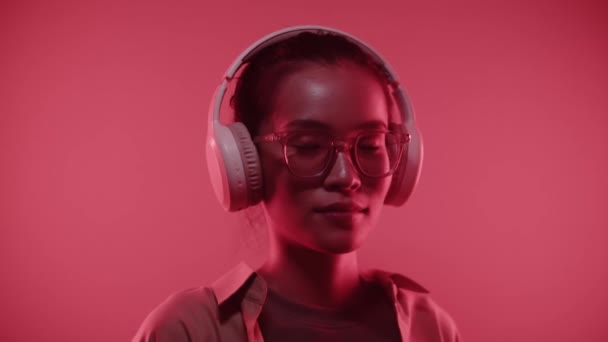 Close Portret Uśmiechniętej Azjatki Słuchawkach Patrząc Kamerę Wewnątrz Czerwone Neonowe — Wideo stockowe