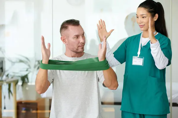 Rehab Sjuksköterska Visar Patienten Hur Man Gör Armträning Med Resistensband — Stockfoto