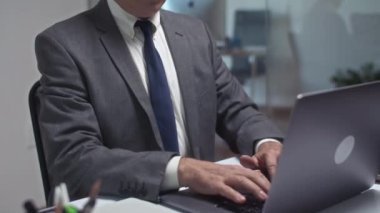 Modern ofiste kablosuz bilgisayarla çalışan dalgın kıdemli iş adamının portresini kaldır ve kameraya bak.