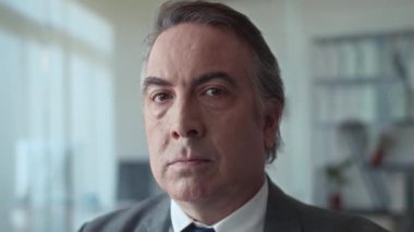 Ofiste çalışırken kameraya bakan ciddi bir iş adamının portresini kapat.