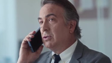 Ofiste çalışırken akıllı telefon kullanarak müşteriyle konuşan yaşlı erkek yöneticiyi kapat