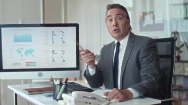 Ofisteki blogu için video çekerken kamerada iş grafiği hakkında konuşan bir finans uzmanının orta boy görüntüsü.