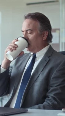 Ofiste molada plastik bardaktan kahve içen düşünceli erkek girişimcinin dikey yavaşlaması
