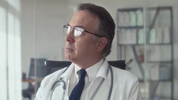 Portret Poważnego Dojrzałego Lekarza Ogólnego Okularach Patrzącego Kamerę Podczas Pracy — Wideo stockowe