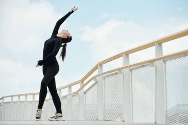 Siyah takım elbiseli genç bir sokak dansçısı dans adımları atıyor.