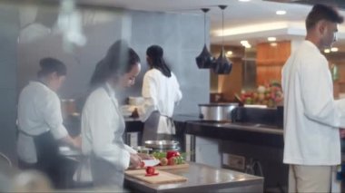 Hat ekibinden orta boy aşçılar, birlikte kafeteryada çalışırken misafirler için yemek hazırlıyorlar.