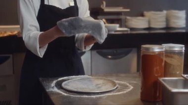 Tanımlanamayan kadın pasta şefinin hamur yoğurması ve restoranın mutfağına teneke konserve koyması.