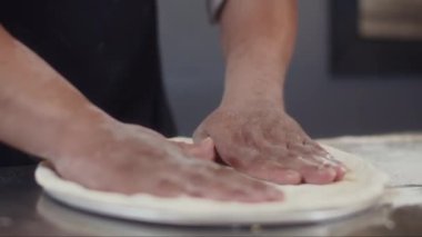 Pizzayı pişirirken çiğ hamuru pişirmek için hazırlayan tanınmayan şefin ellerini kapatın.