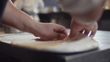 Yemek pişirirken hamur hamurunun kenarlarını düzleştiren tanınmayan pizzacının ellerini kapatın.