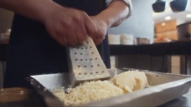 Cafe 'de müşteriler için çalışan peynir yerine rende kullanan tanınmayan aşçının ellerini kapatın.