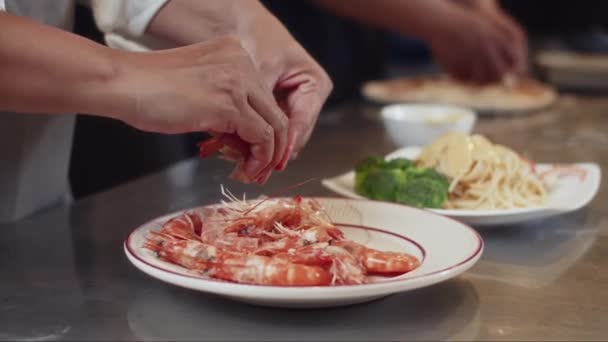 レストランキッチンでテーブルでシーフードパスタを調理しながら シェフの手をクローズアップ — ストック動画